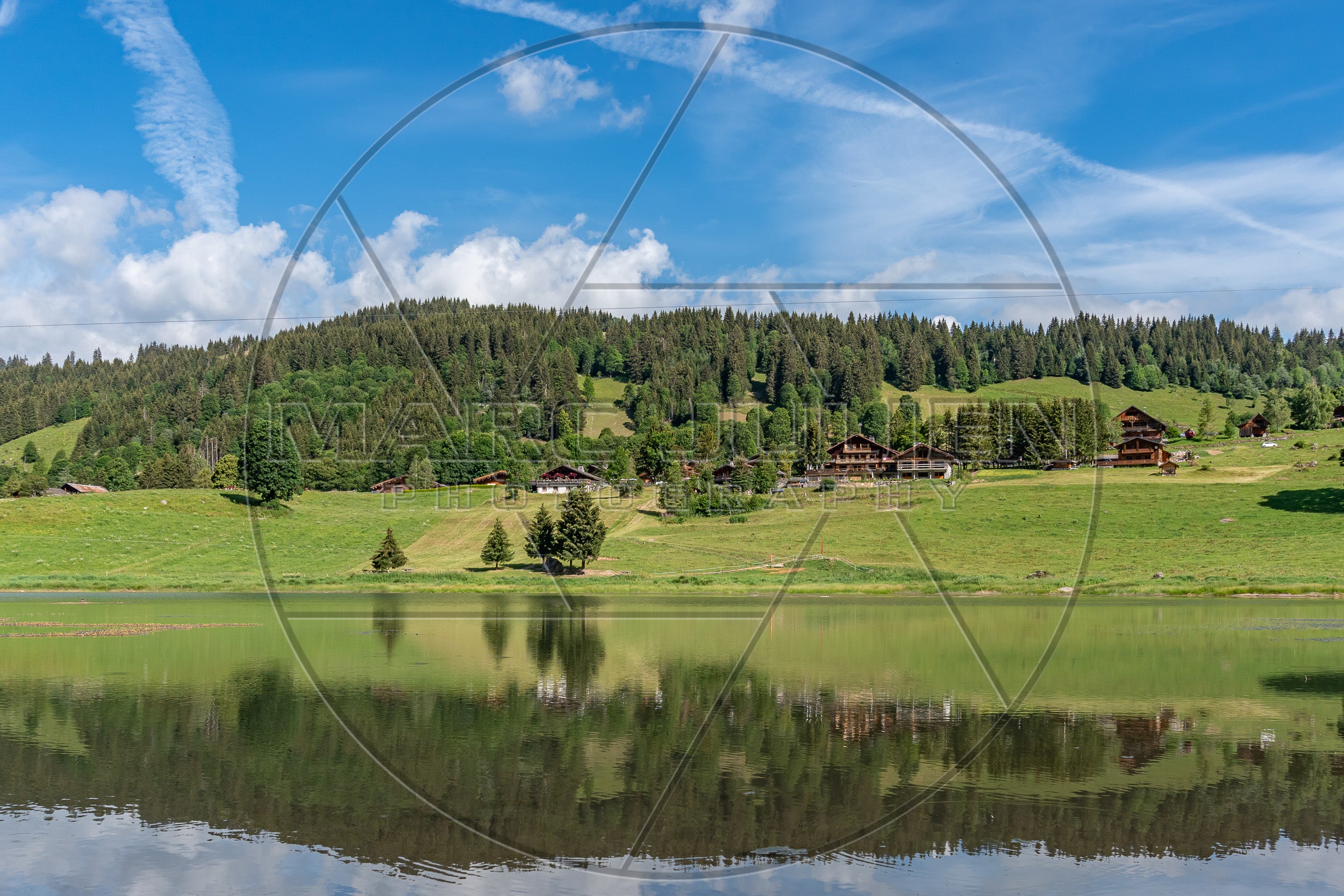 Bergsee umgeben von Chalets und grünen Wiesen