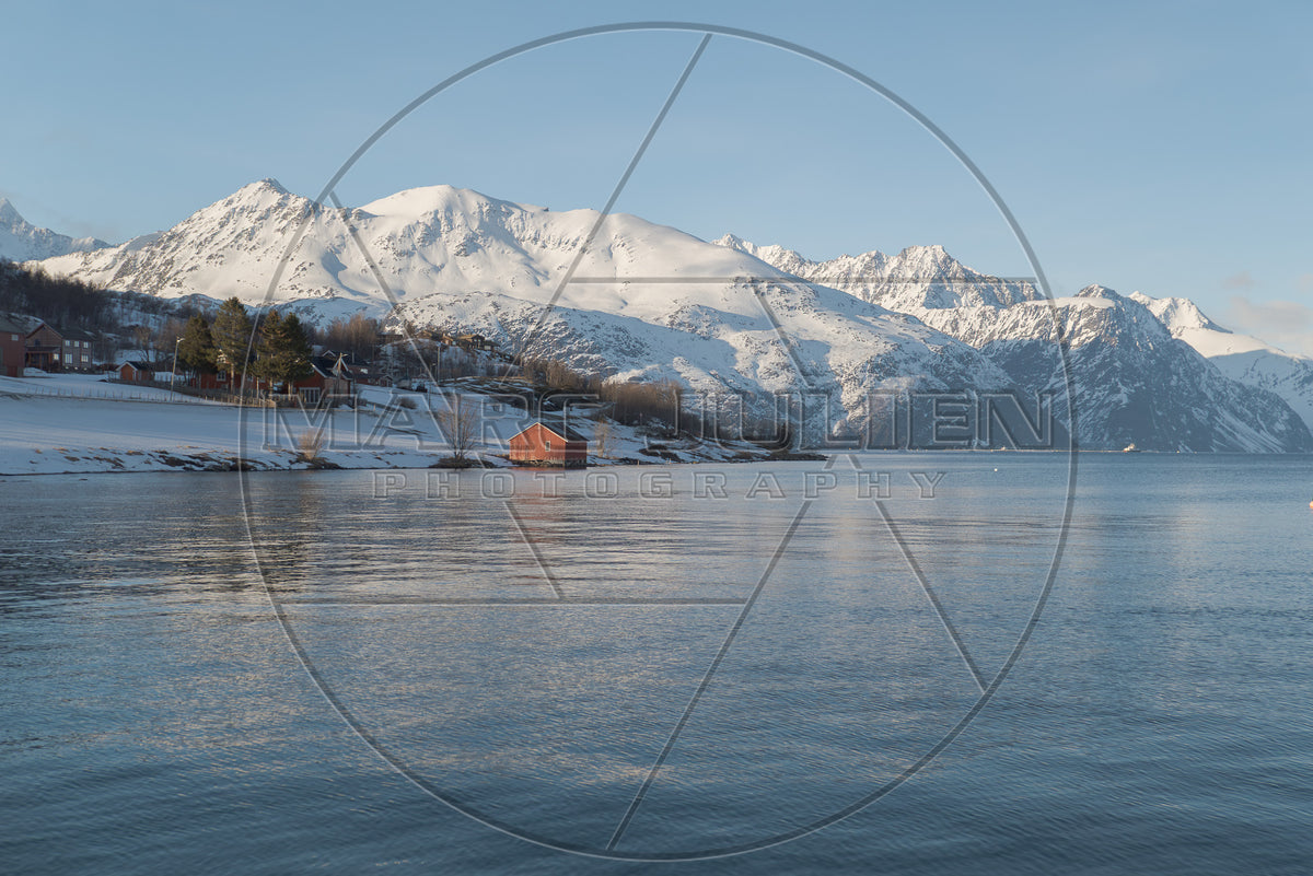 Norwegian fjord in winter with snow-covered mountains and village