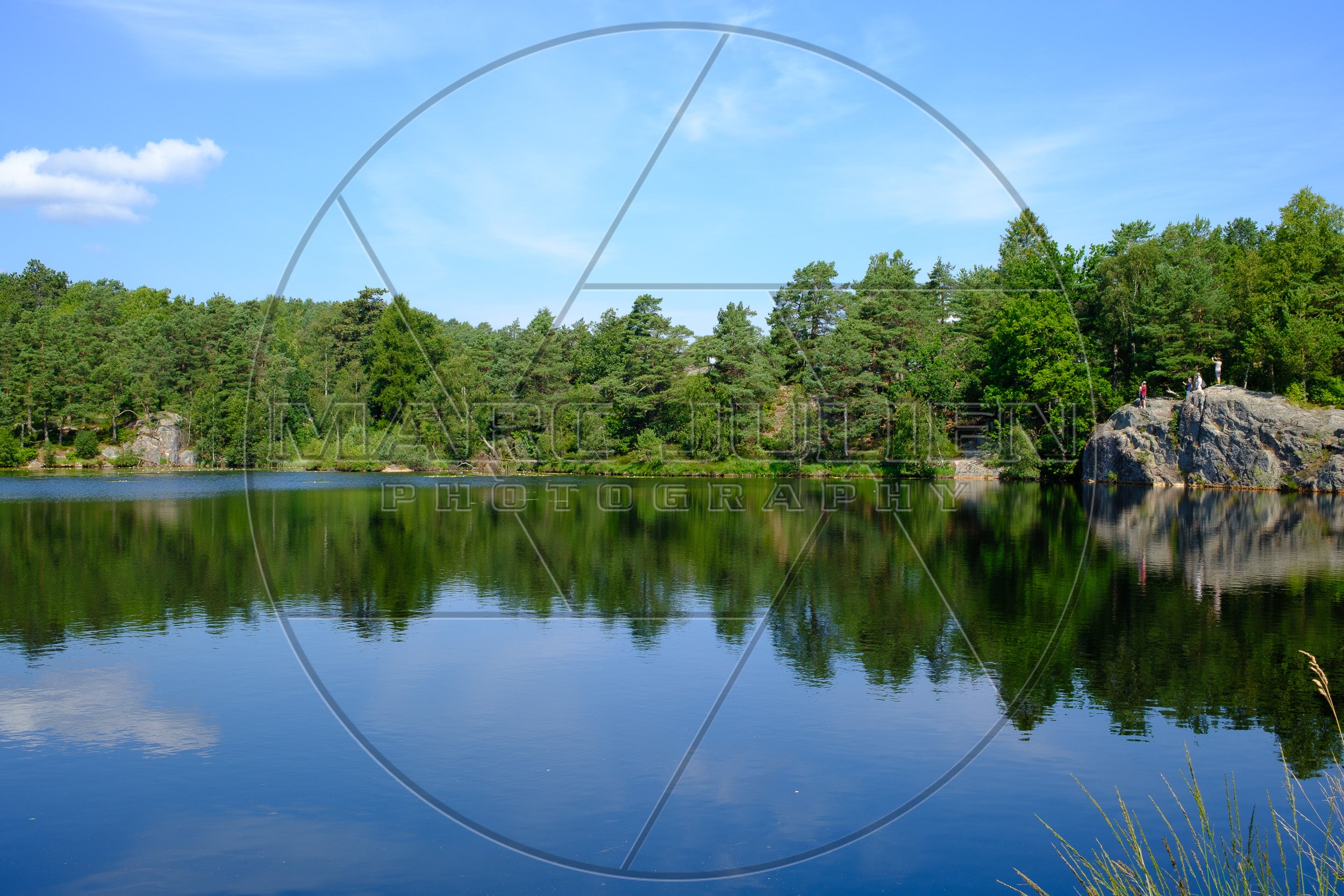 Waldsee und Granitfelsen unter blauem Himmel