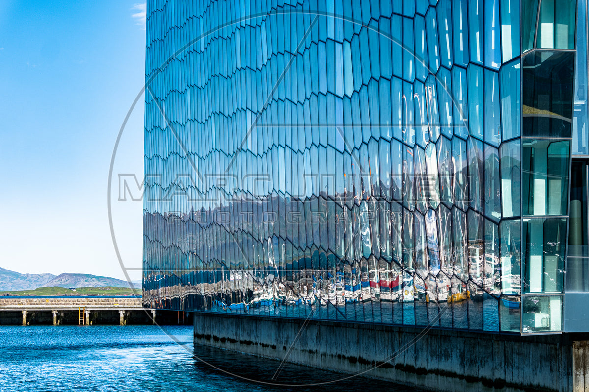 Façade vitrée géométrique au bord de l’eau et reflets du paysage
